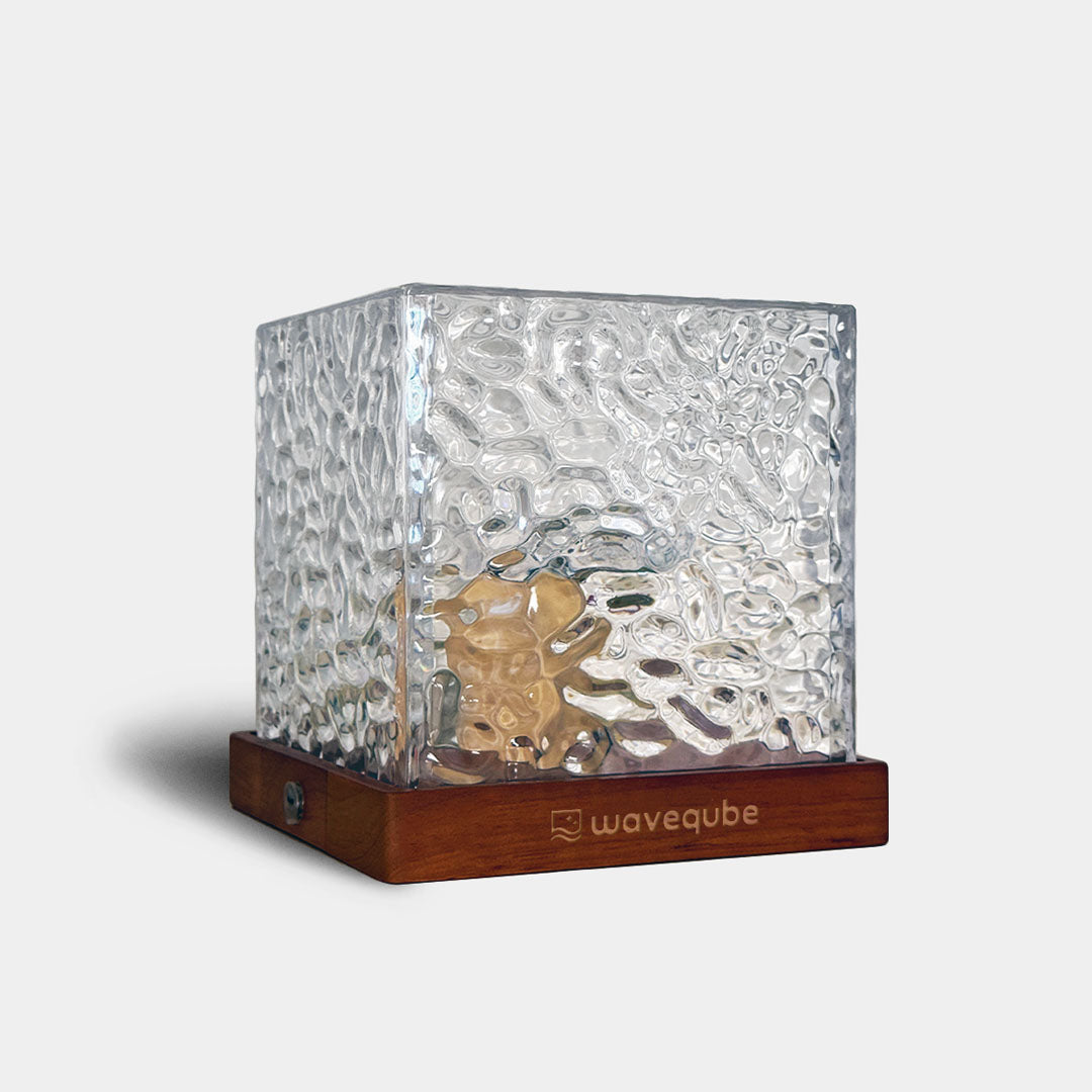 Glass cube with water design and walnut wooden base on a white background, featuring the brand 'waveqube' also known as the wave lamp.